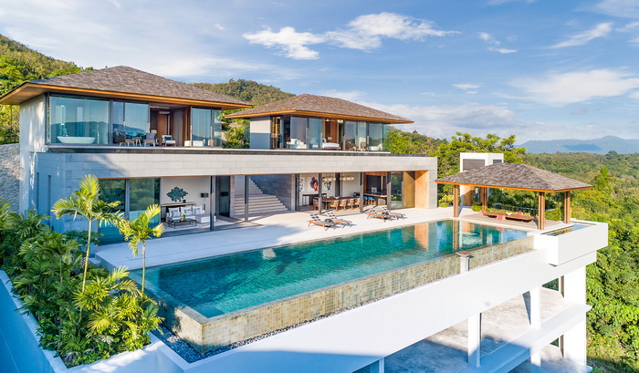 An infinity pool overlooking the ocean, with a couple lounging on the edge